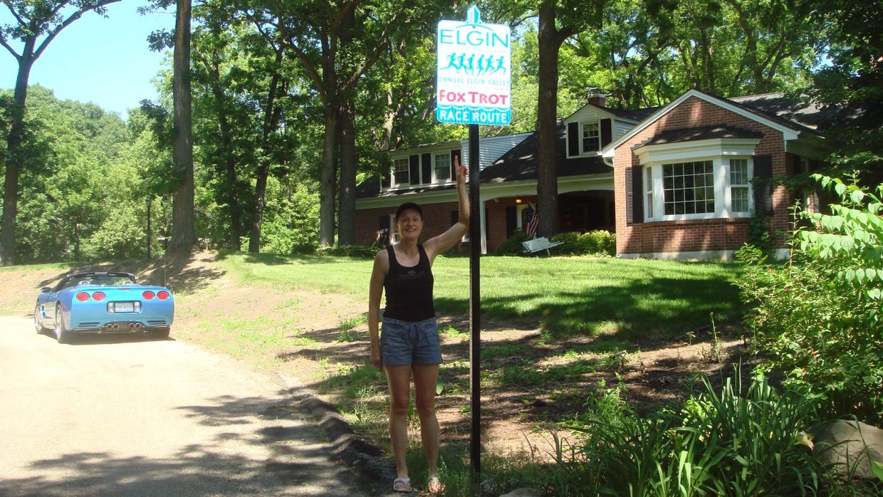 Woman standing by an Elgin Fox Trot race route sign.