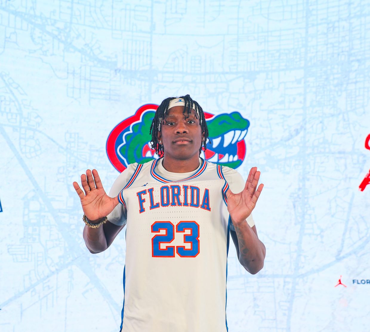 Basketball player in Florida Gators jersey number 23 posing with hands raised.