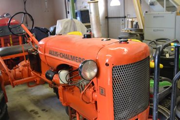 Vintage orange Allis-Chalmers tractor in a workshop.