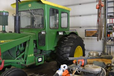 Green John Deere tractor parked inside a garage.