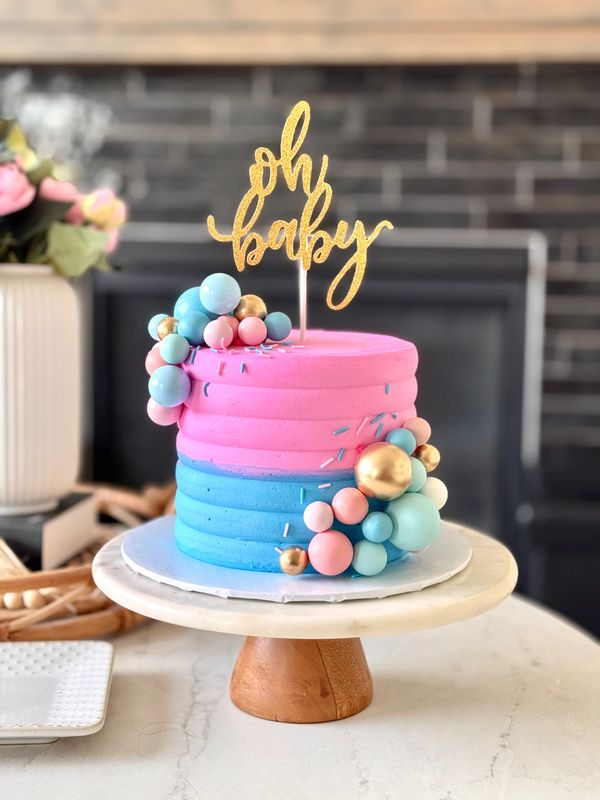 Pink and blue gender reveal cake with gold "oh baby" topper.