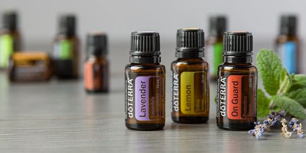 Three essential oil bottles labeled Lavender, Lemon, and On Guard on a wooden surface.