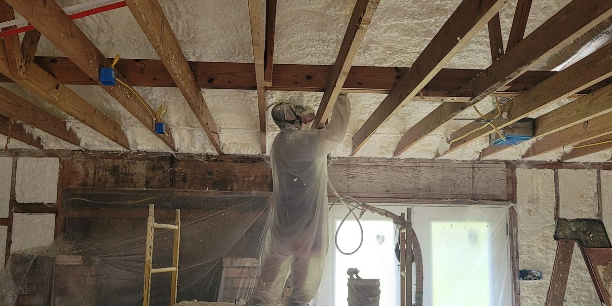 Worker sprays foam insulation on ceiling.