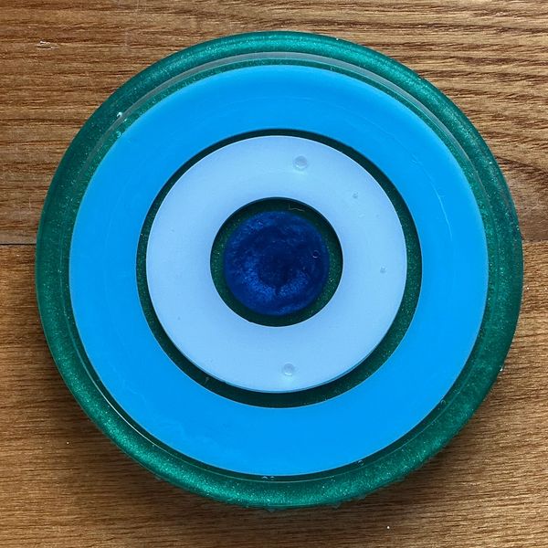 A circular evil eye amulet on a wooden surface.