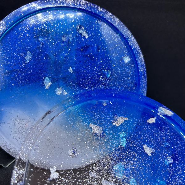 Two blue resin coasters with silver flakes and glitter.