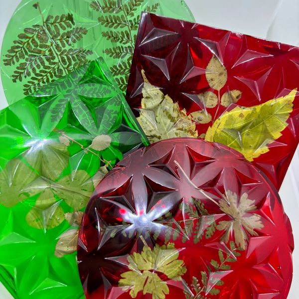 Decorative resin trays with embedded leaves in red, green, and clear colors.