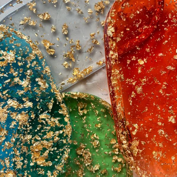 Colorful resin pieces with gold flakes embedded inside them.