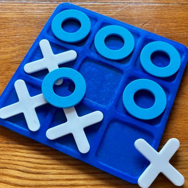 Tic-tac-toe game with blue and white pieces on a blue board.