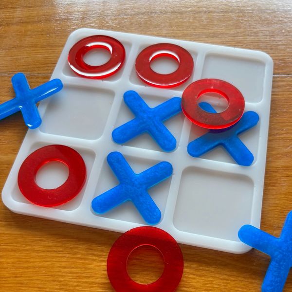 Tic-tac-toe game with red O's and blue X's on a white board.