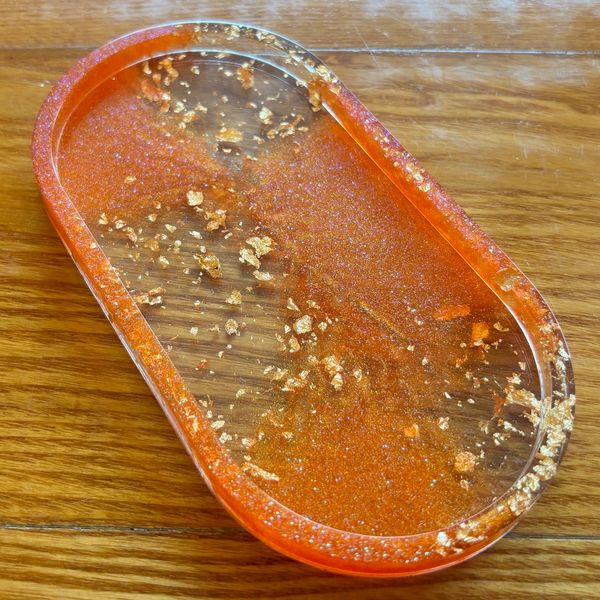 Orange and gold decorative resin tray on wood.