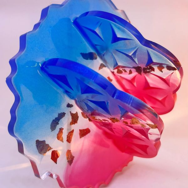Colorful translucent butterfly sculpture with blue and pink hues and gold flakes.