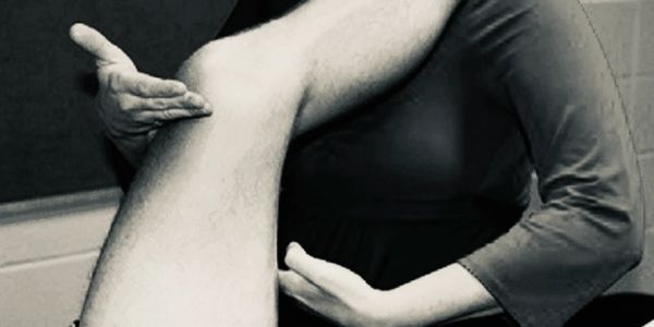 Physiotherapist assisting with leg stretch during therapy.