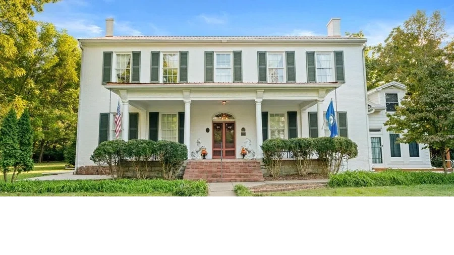White colonial-style house with green shutters and front porch.