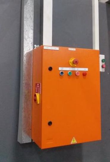 Orange industrial control panel mounted on a wall with buttons and emergency stop.