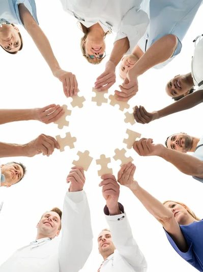 A diverse group of medical professionals holding puzzle pieces in a circle.