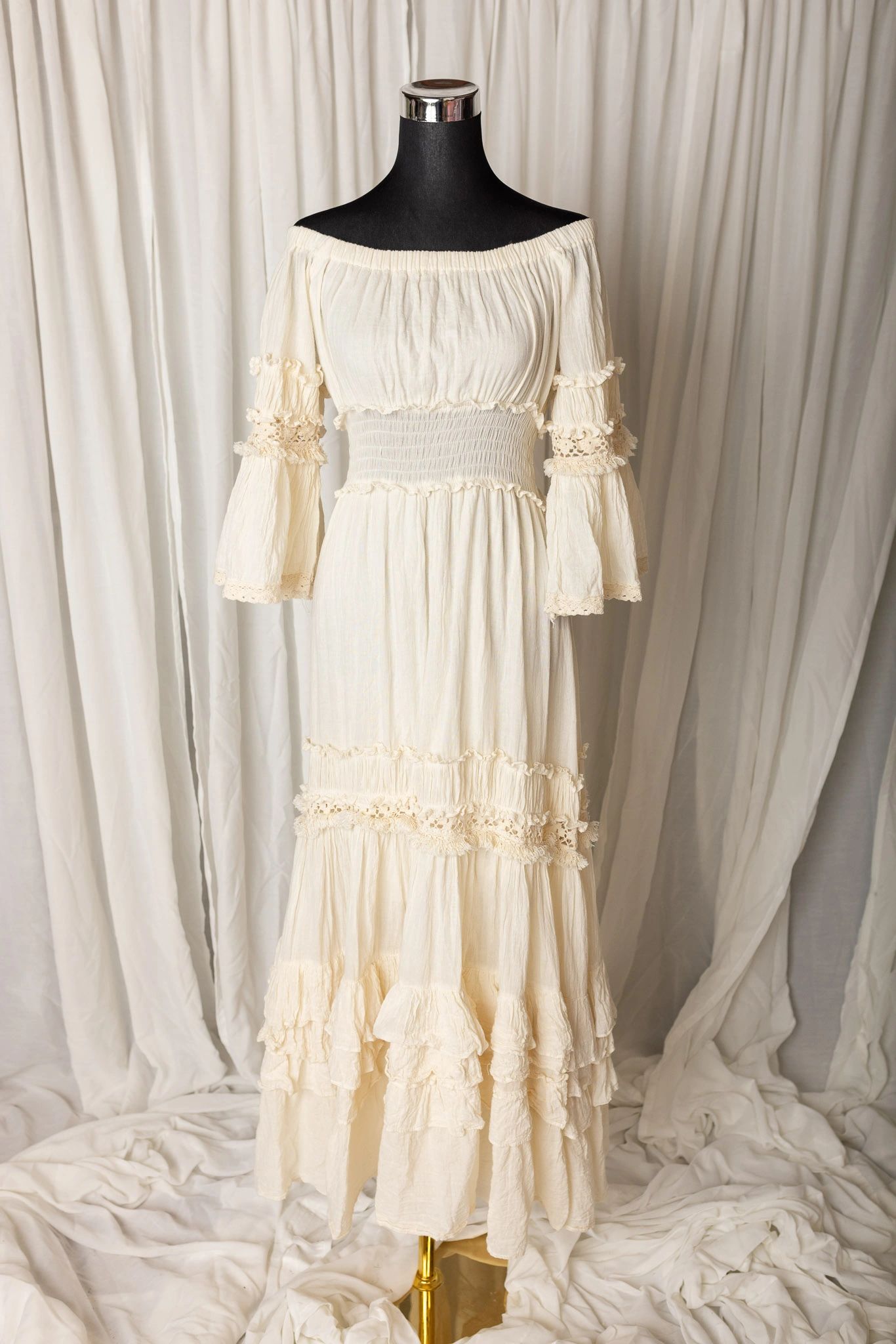 Off-white bohemian dress with ruffles and lace details.