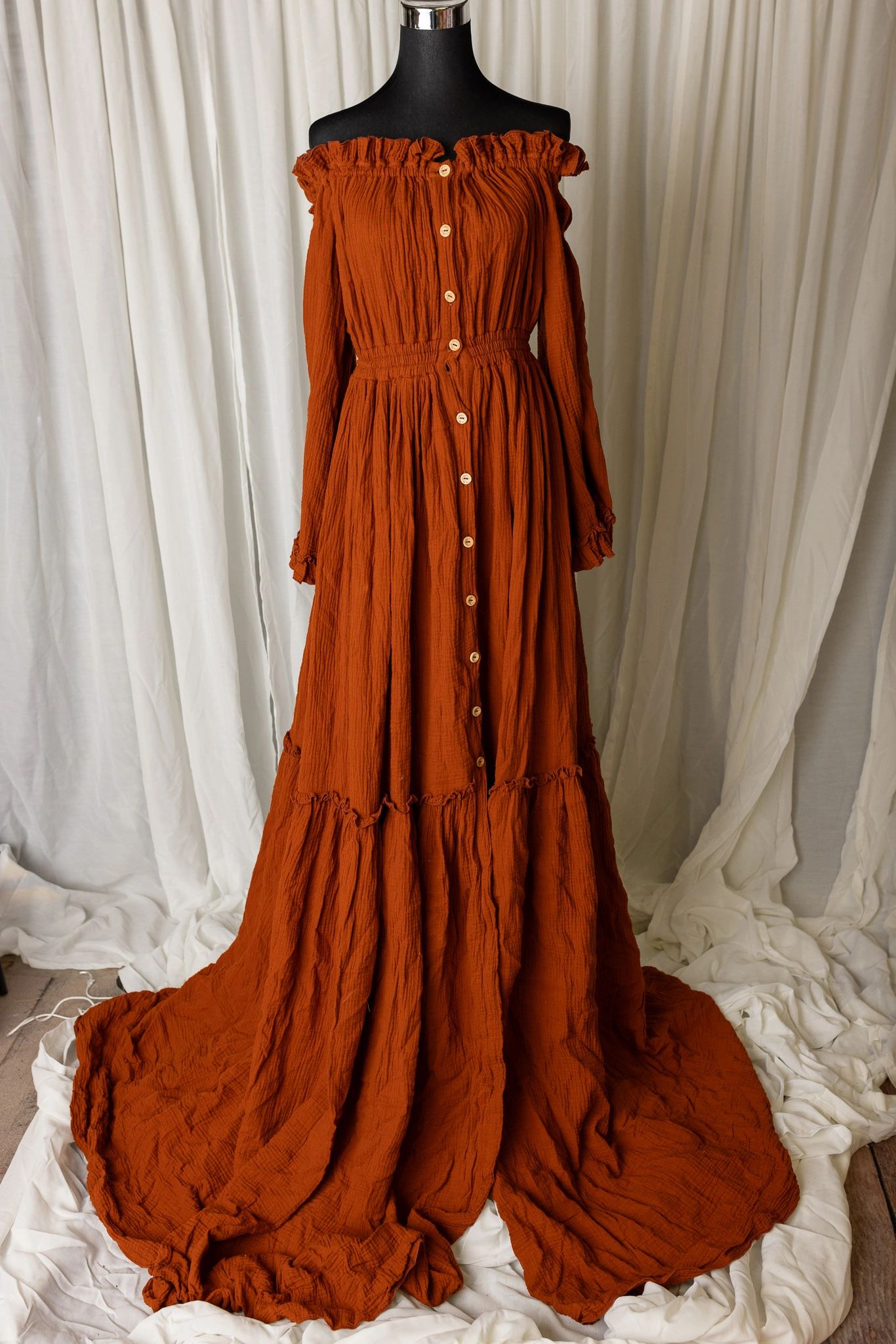 Rust-orange off-shoulder button-down dress on mannequin.
