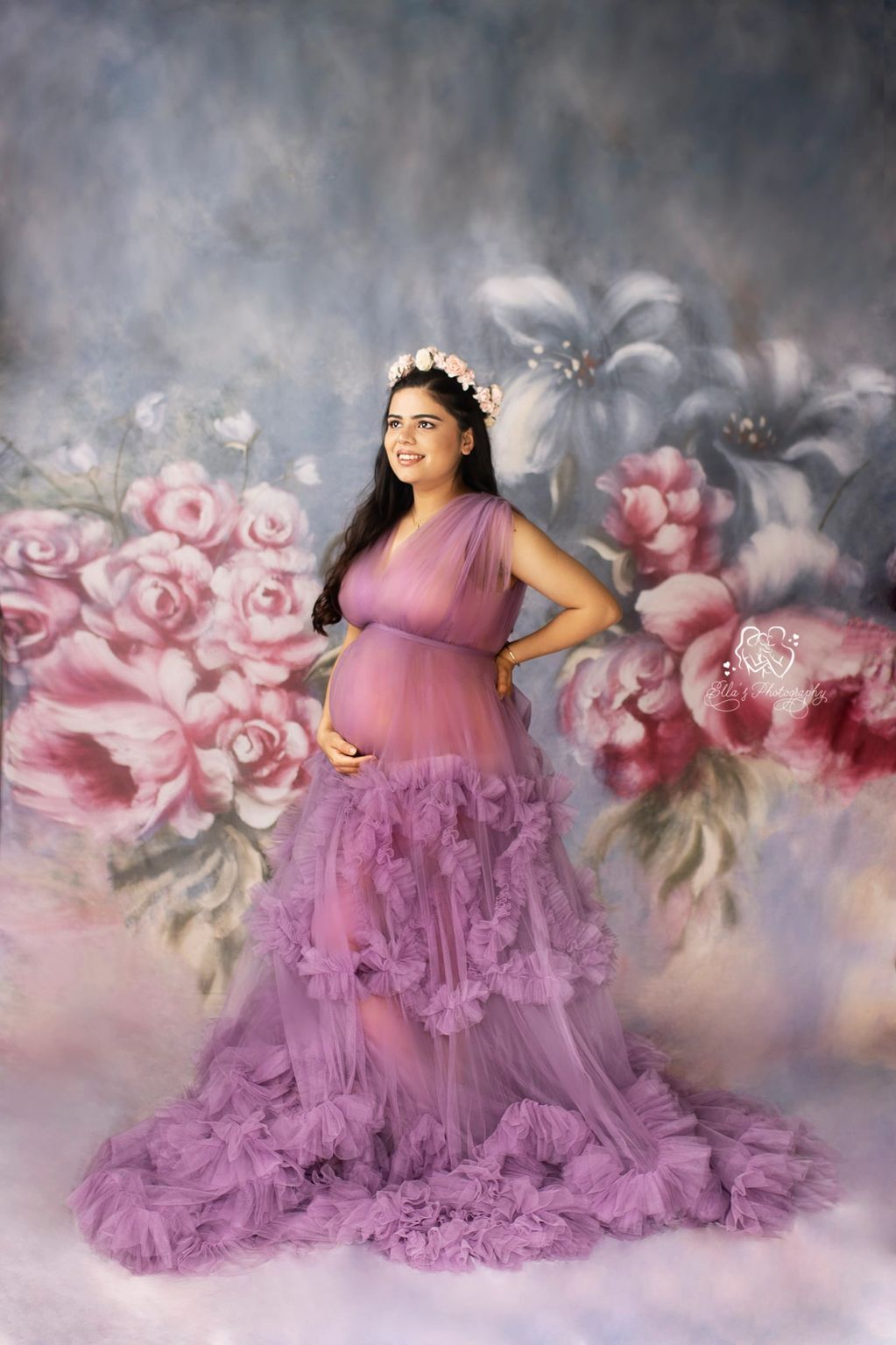 Pregnant woman in a purple gown with floral background.