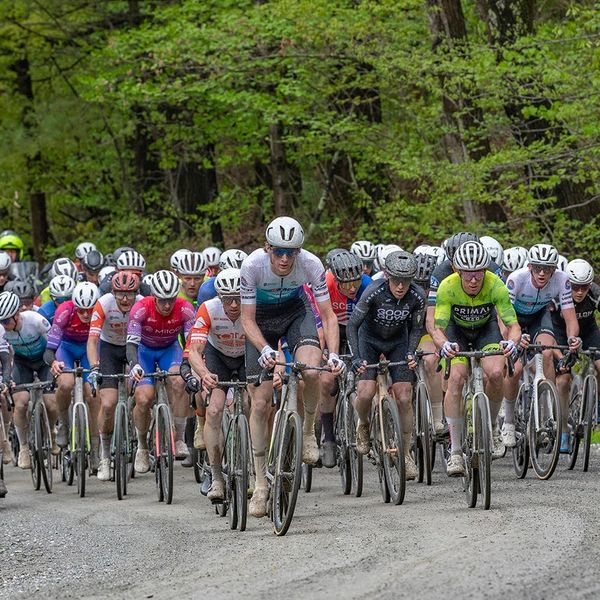 Cyclists racing on a forest trail during a competitive event.
