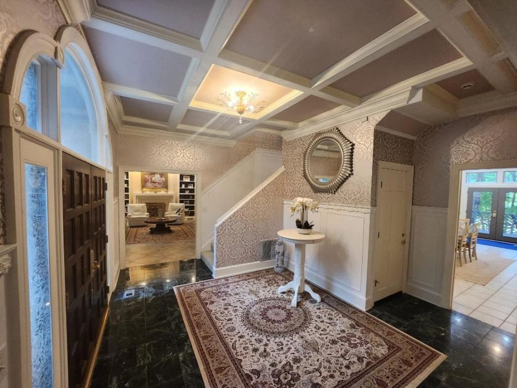 Vankirk Home Upgrades' master carpentry offers specialization for any space, custom built-ins, finish trim and moldings, and upscale refinement. This elegant foyer with glamorous, patterned wallpaper showcases subtle metallic sheen, ornately crafted coffered ceiling detail, intricate crown moldings, finish trims, wainscoting/ judge's panel, marble tile flooring, semi-flush crystal chandelier, and soft inviting color scheme is reminiscent of French royalty, But all this opulence, glamor, and sparkle are complimented and balanced by the double doors made of rich, rustic, earthy solid mahogany custom crafted doors and the contrasting darkness of the sultry, yet glossy, traditional hunter green marble tile flooring to reflect the homeowner's uniquely royal style. What a beautiful, welcoming, first impression we had the pleasure of creating for this home!