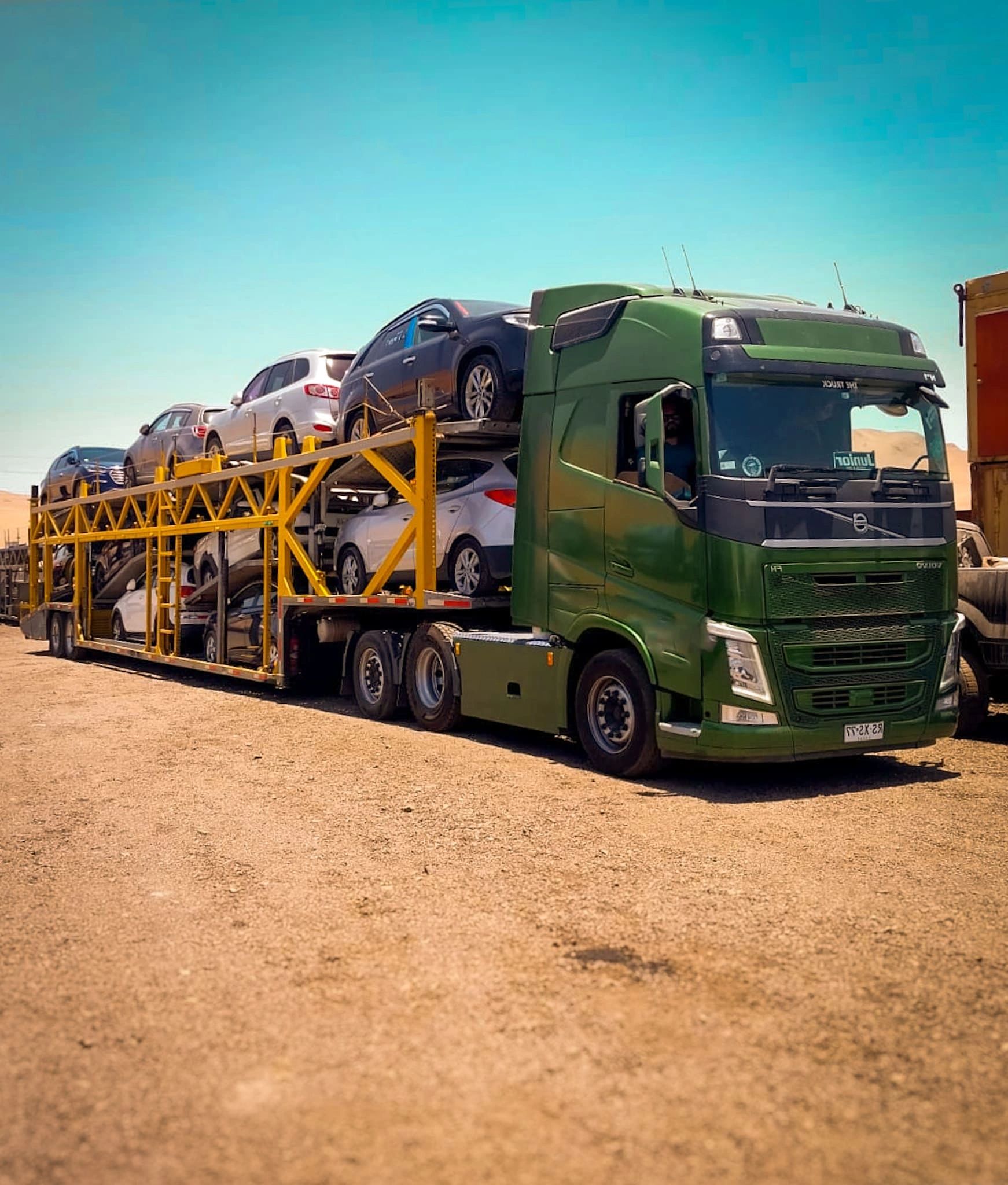 camion verde con rampa cargado con vehiculos
