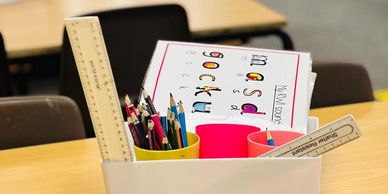 Classroom showing a box with pencils, and rulers.