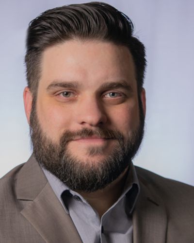 Portrait of a man with a beard in a suit.