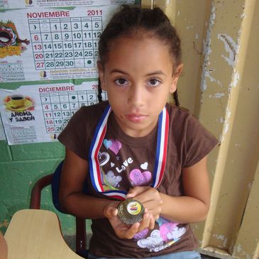 Young girl holding a medal with a serious expression.