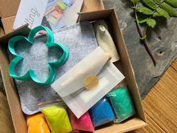 Craft kit with colorful materials and flower-shaped cutter.