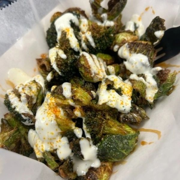 Crispy roasted Brussels sprouts drizzled with creamy sauce and spices.