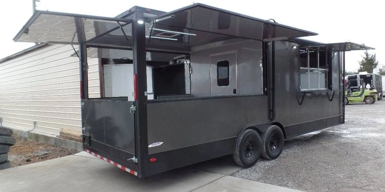 Black mobile food trailer with open serving windows and dual axles.