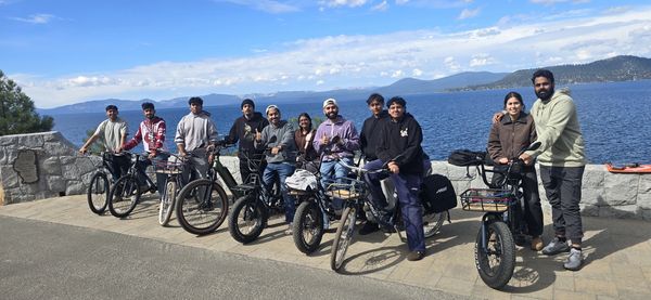 Group of people on electric bikes by the water.