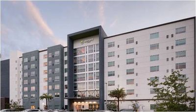 Modern hotel building with palm trees at dusk.