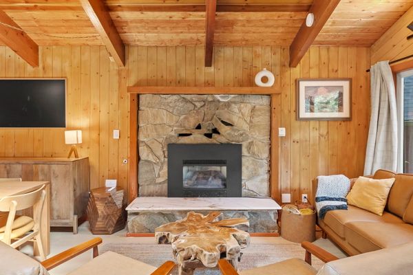 Rustic cabin-style living room with stone fireplace – unwind by the fire after a hike.