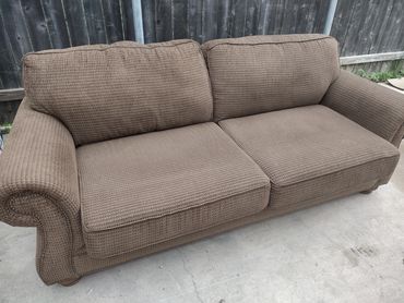 Brown fabric sofa with rolled arms outdoors.