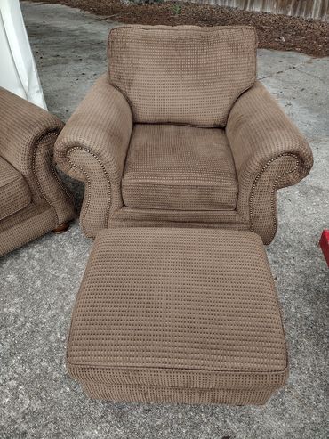 Brown upholstered armchair with matching ottoman outdoors.