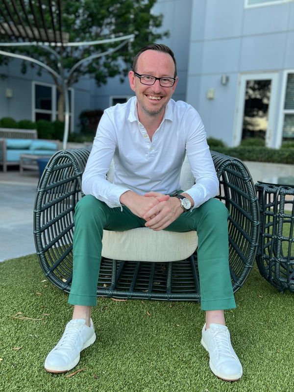 Man sitting on outdoor wicker chair smiling.