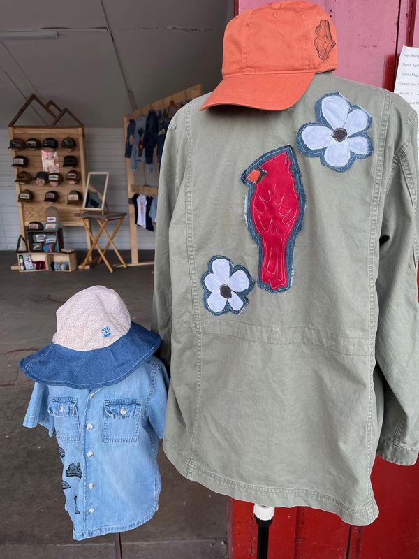 Two mannequins wearing decorated jackets and hats in a clothing store.