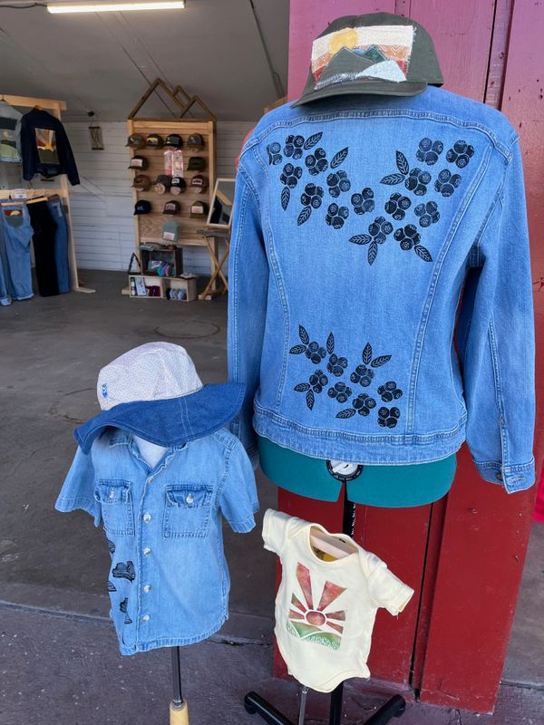 Denim jackets and a baby onesie with hats displayed on mannequins, original Made in the Image Studio.