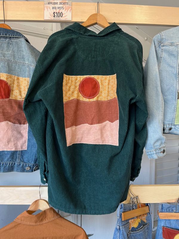 Green corduroy jacket with colorful geometric applique on the back, priced at $100.