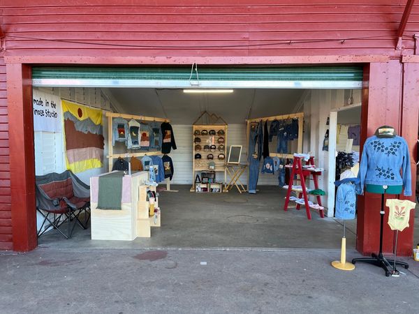 Artisan clothing and accessories displayed in an open garage market stall.