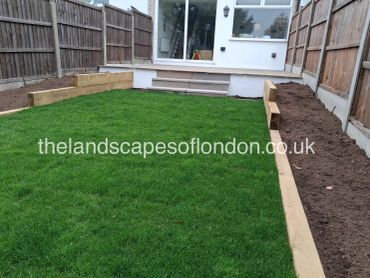 Freshly landscaped backyard with green lawn and wooden garden beds along fences.