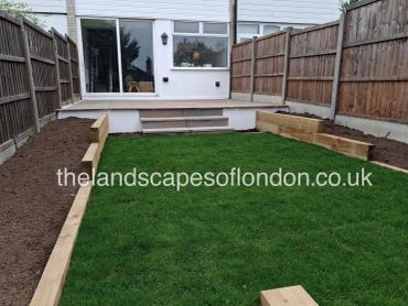 Newly landscaped backyard with fresh grass and wooden garden beds.