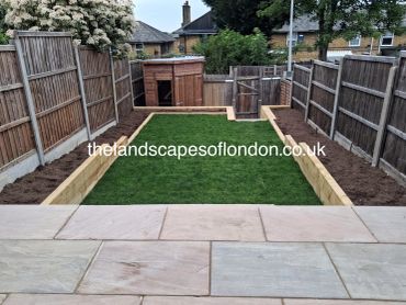 A neatly landscaped garden with green grass and wooden borders.