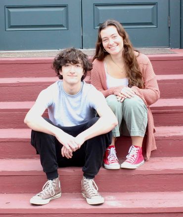 Two young people sitting on red steps, smiling warmly.