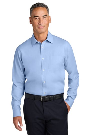 Man in light blue dress shirt and black pants posing confidently.