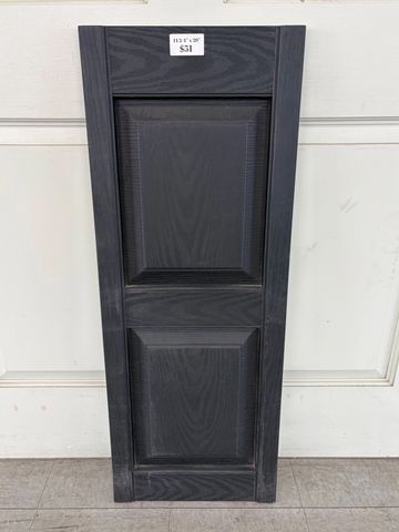A tall, black wooden cabinet door with two recessed panels.