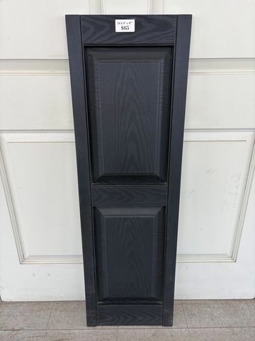 Tall black wooden cabinet door panel leaning against a white door.