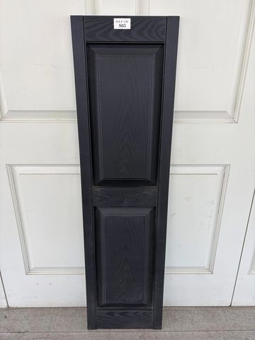 Tall black wooden cabinet door leaning against white doors.