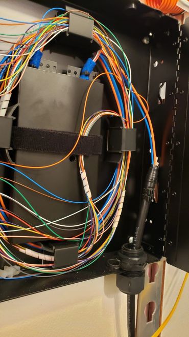 Fiber optic cables organized inside a black enclosure.